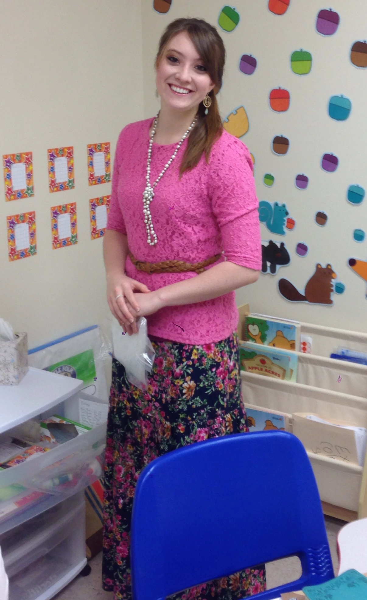Kendra in a children's classroom decorated with paper acorns and woodland animals